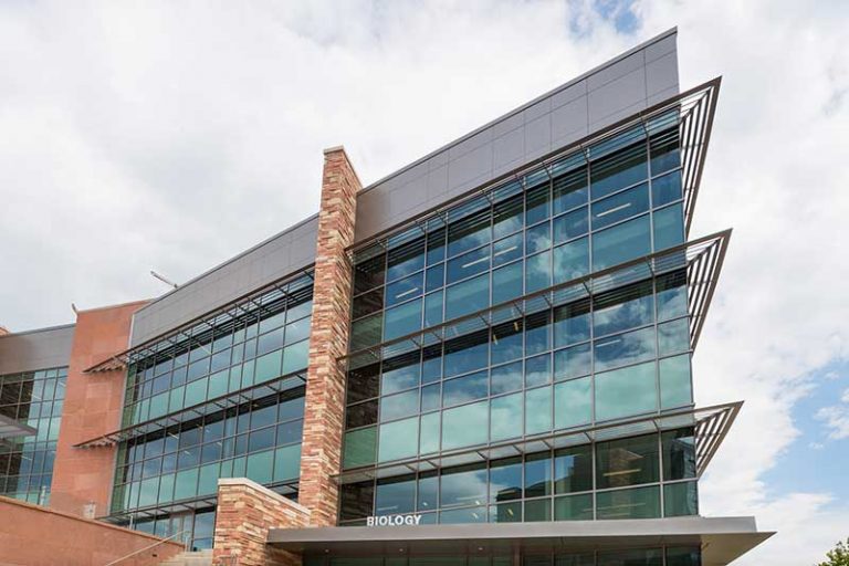 The Biology Building at Colorado State University, featuring a modern glass and stone exterior with sharp architectural lines and reflective windows.