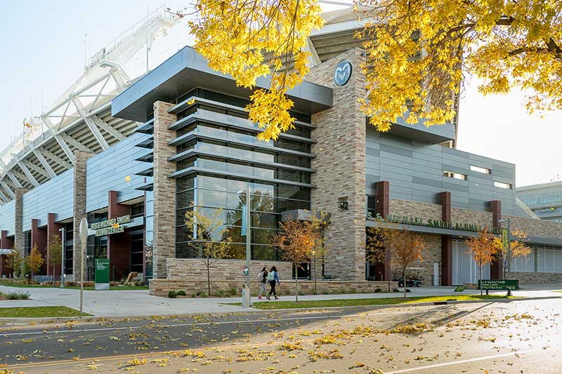 Canvas Stadium at Colorado State University on a sunny autumn day, with modern architecture and fall foliage in the foreground