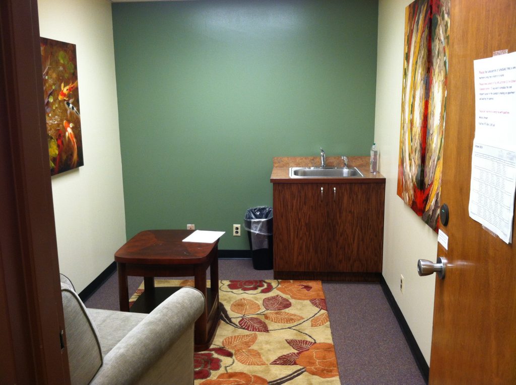 Lactation Room in General Services Building, includes armchair, carpet, low table, and sink. Artwork on walls.