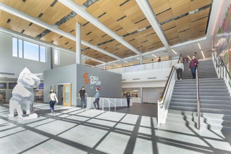 Interior of the Vida building at CSU Spur in Denver, Colorado, showing a large staircase, modern design, and a geometric animal sculpture near the CSU Spur logo.