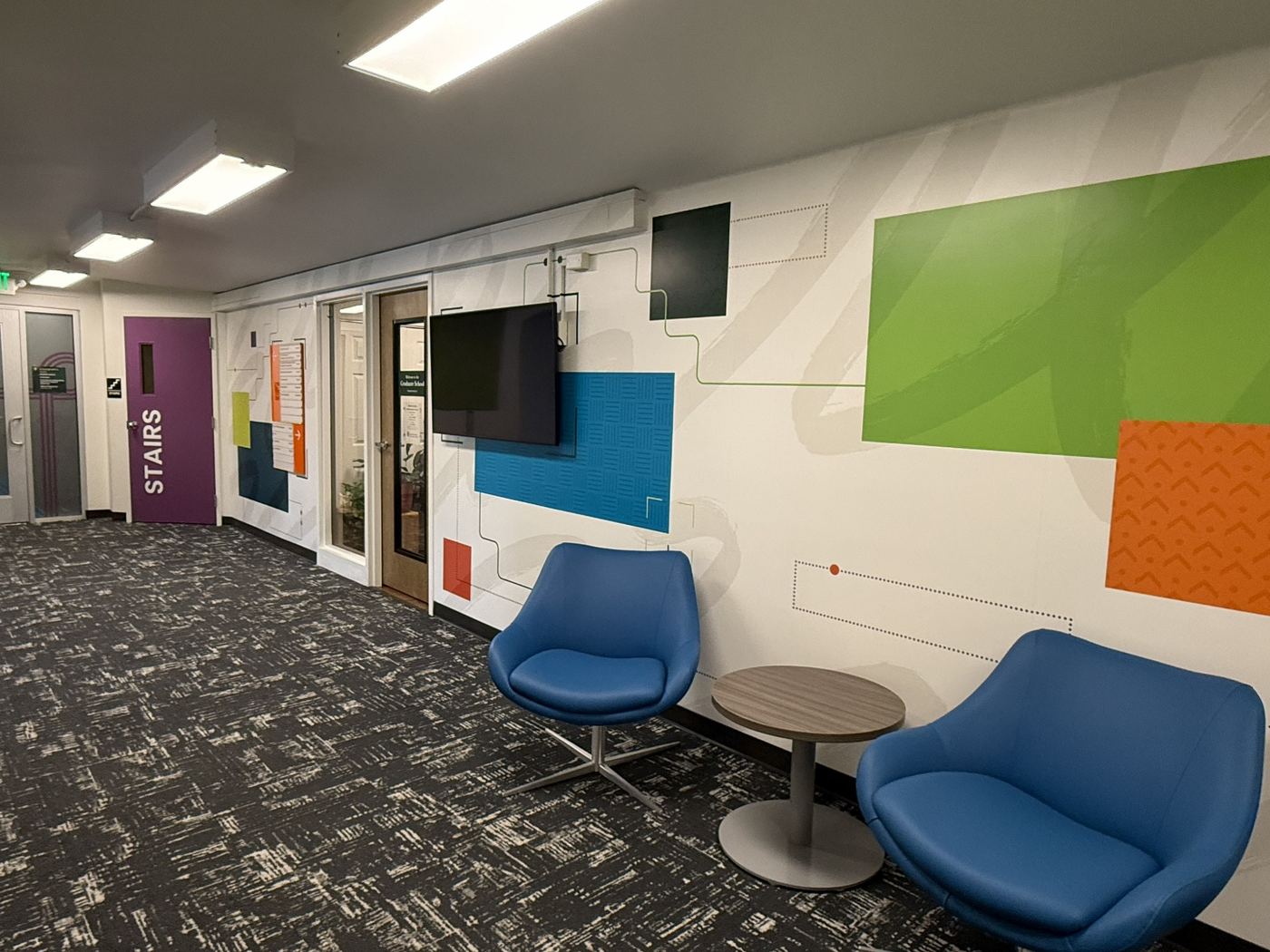 Remodeled lobby and reception area with updated furniture, wall graphics, finishes, lighting, and sound panels.