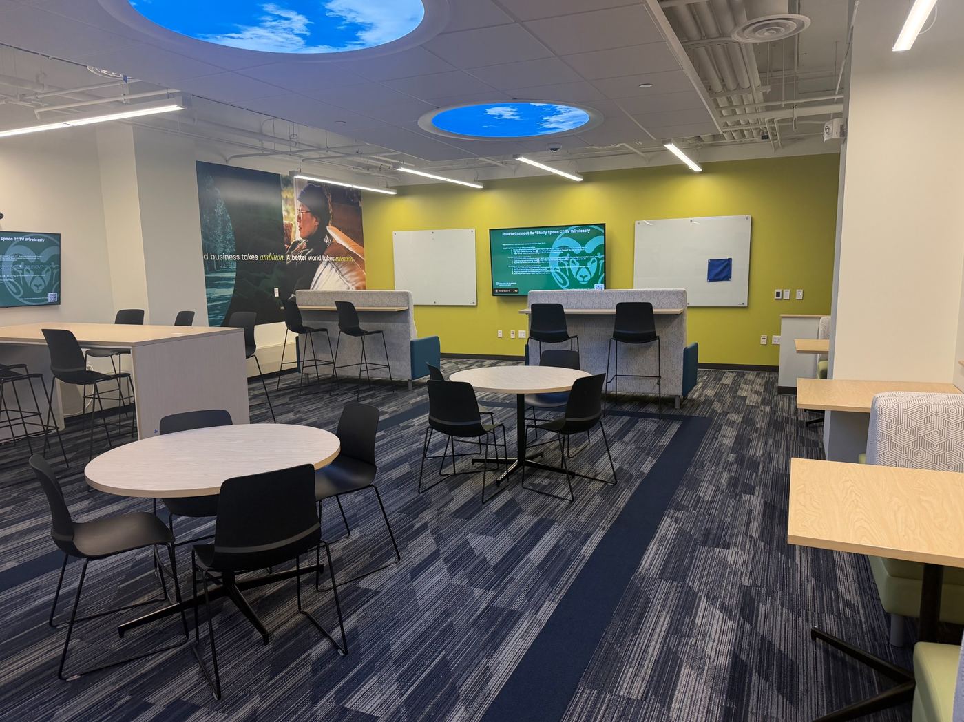 Collaborative student study space with LED cloud lights, flexible seating, and interactive monitors.