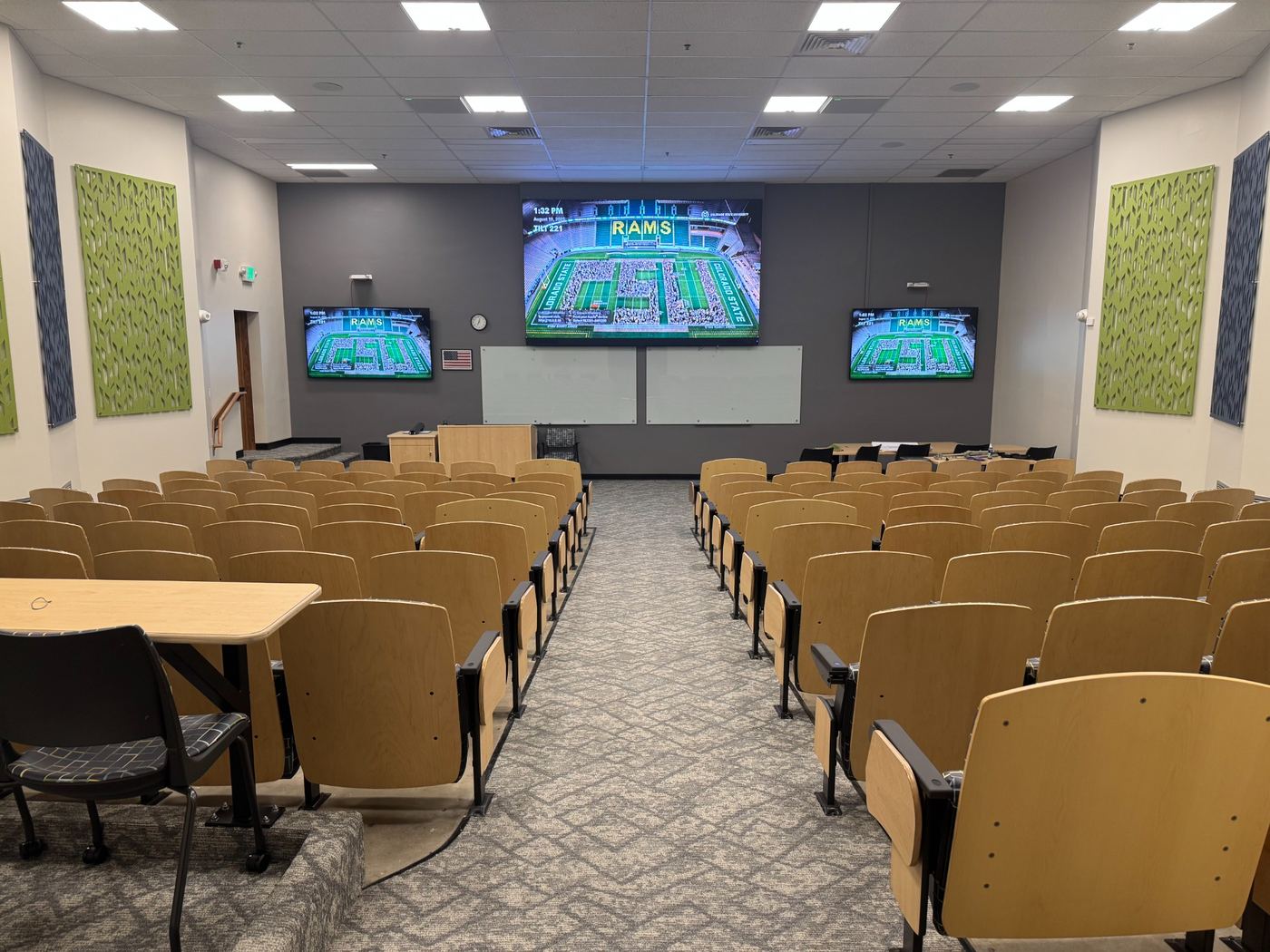 Renovated lecture hall with new seating, finishes, sound panels, glass boards, lighting, and large LED video wall.